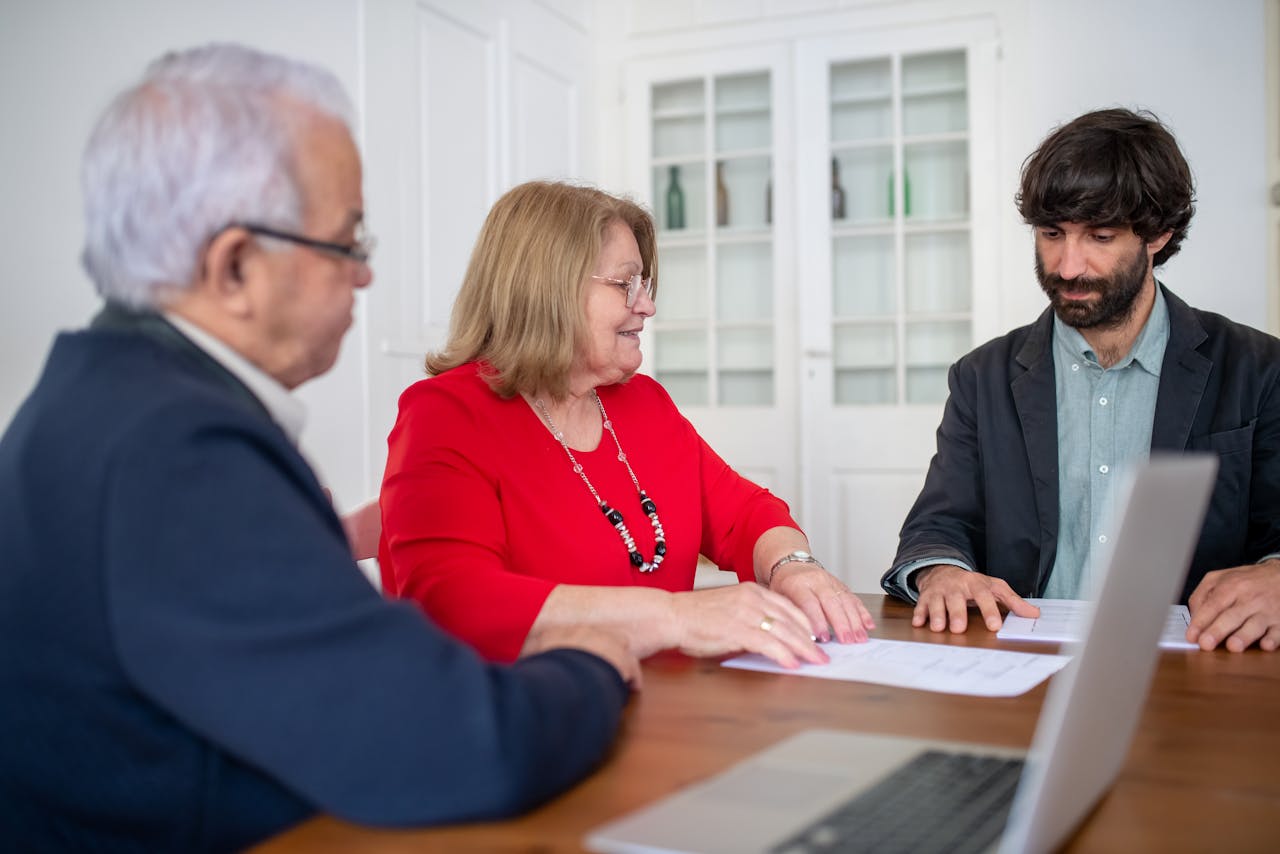 Three business professionals in a meeting, discussing documents and planning strategies indoors.